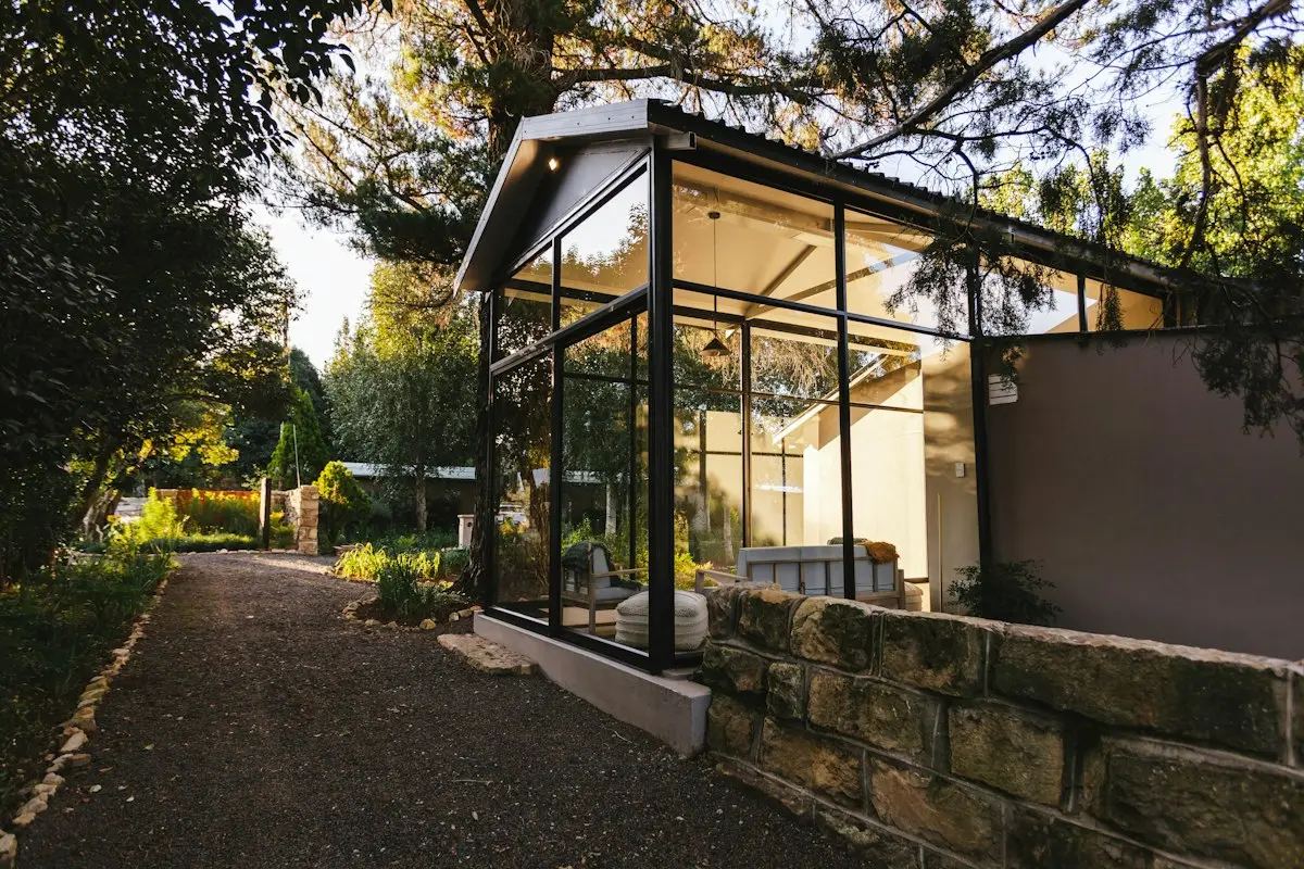 Orangery with slim black frames beside a garden path