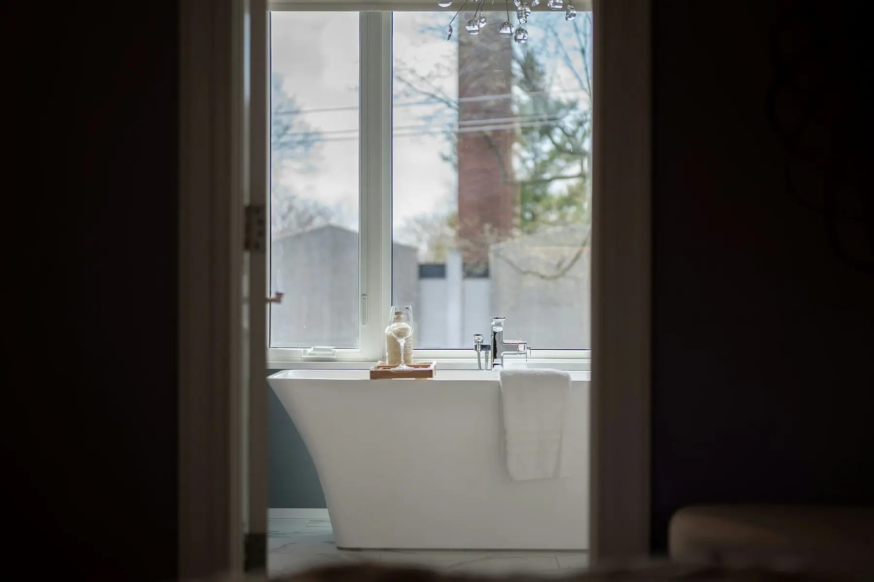 Freestanding bath beneath a tall window in a dark bathroom