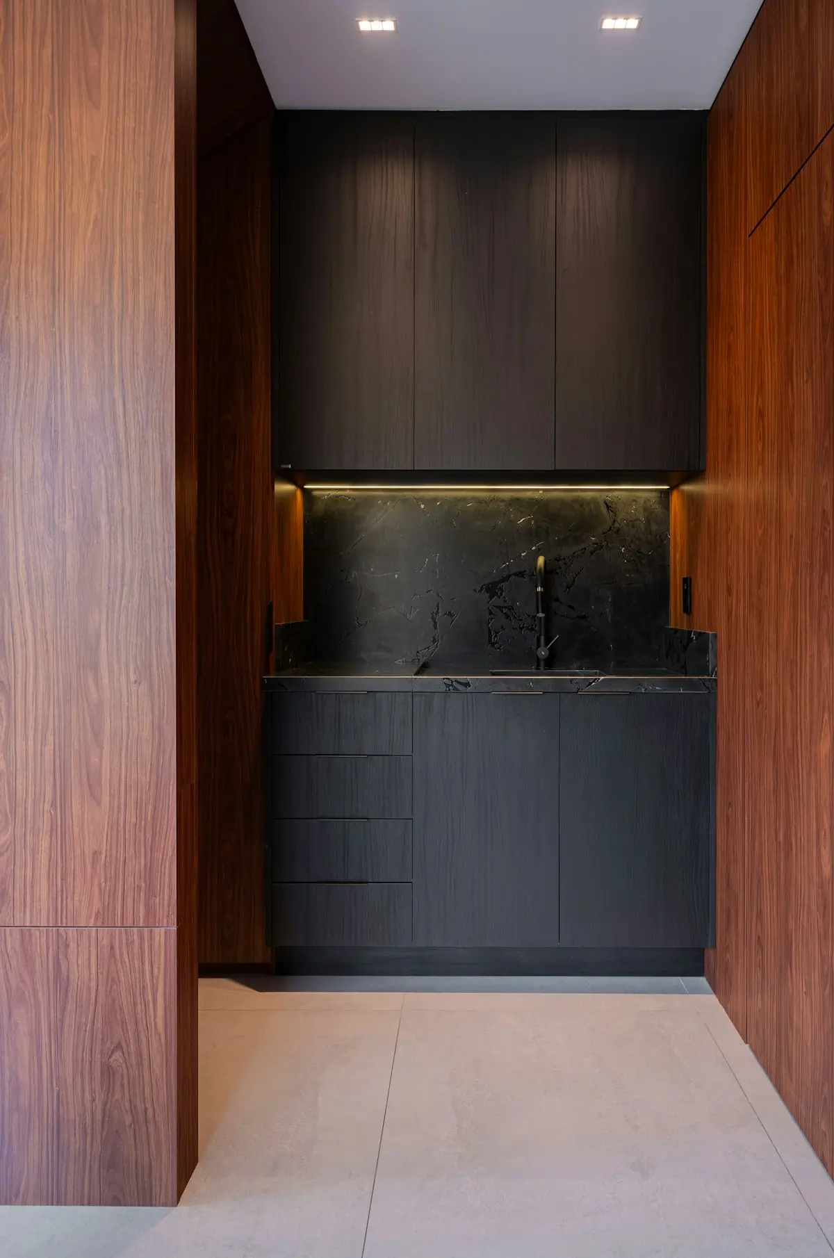 Walnut panelling framing a black kitchen