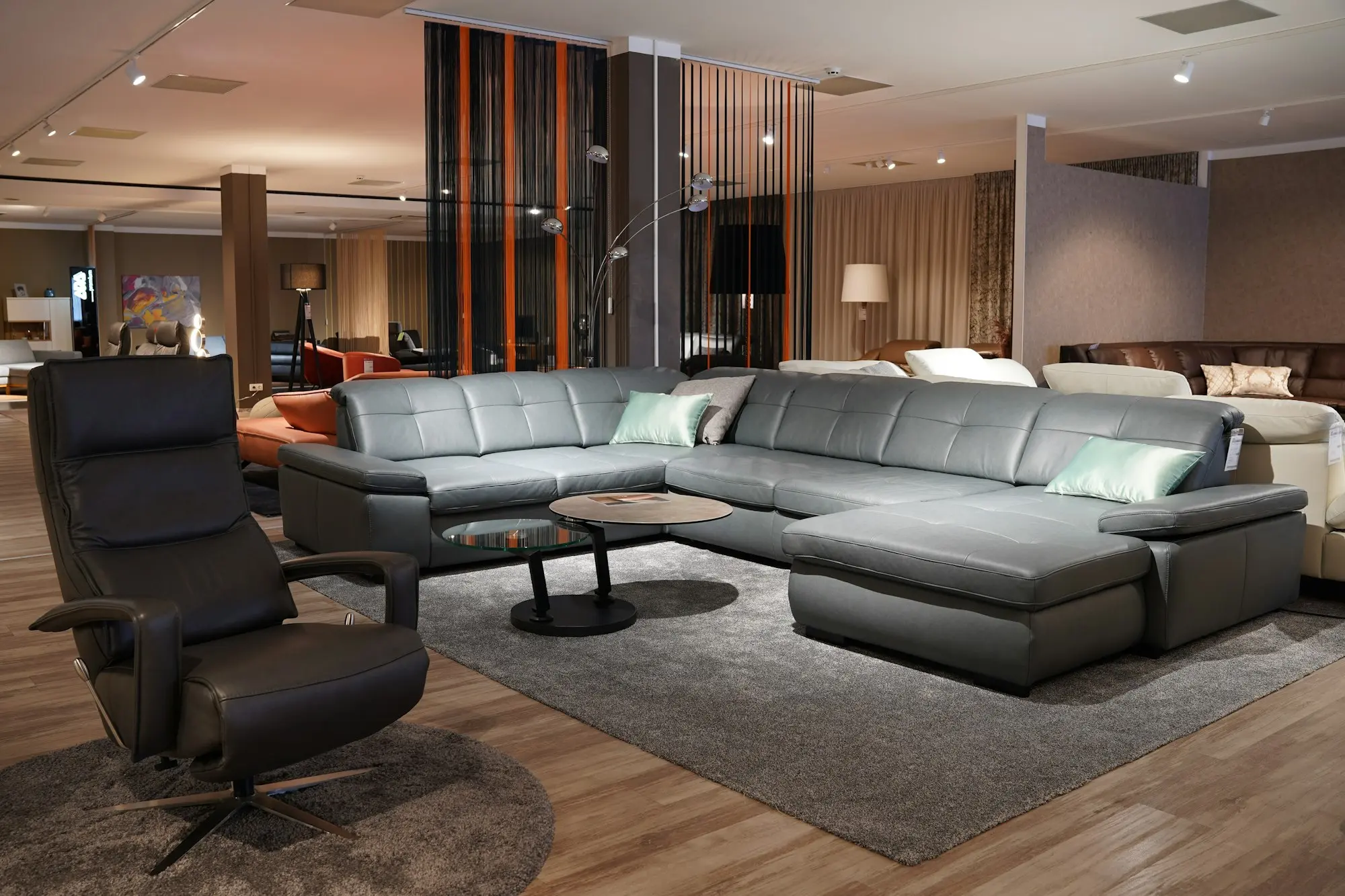 Showroom floor with a grey corner sofa and leather recliner